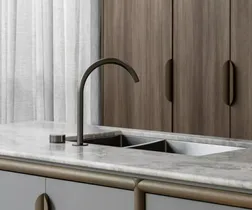 Tap on bench in kitchen with stone benchtop and timber cabinetry