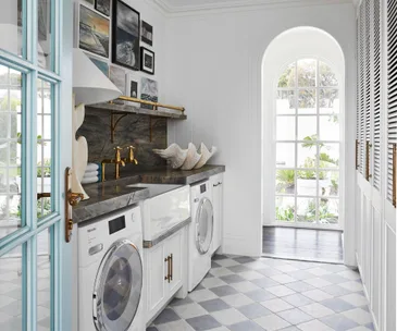 A coastal-style laundry with checkerboard flooring and a gallery wall