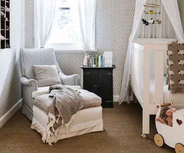 babys nursery with white palette and grey nursing chair