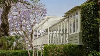 Exterior view of a Longueville Federation home with pergola and jacaranda trees