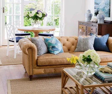 Tan leather chesterfield lounge with blue cushions