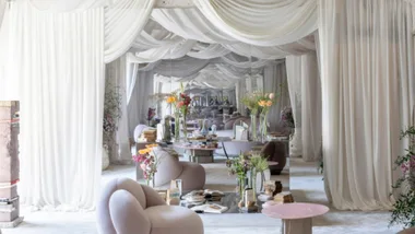 A mirrored corridor in a white living room with draped fabric hanging from the ceiling with soft furnishings throughout.