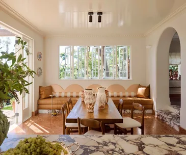 European-style dining area in white and beige, featuring a leather banquette and Calacatta Viola marble.