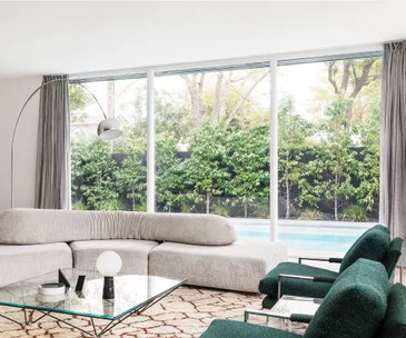 Mid-century living room with big glass windows and view of pool