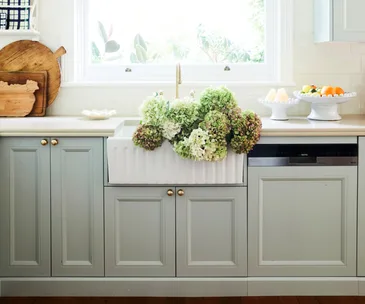 A country-style kitchen with a farmhouse sink and integrated dishwasher