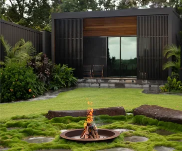 A mossy fire pit area beside a modern villa