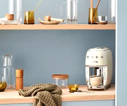 Smeg coffee machine on a wooden kitchen counter with blue walls