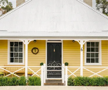 A yellow weatherboard cottage with a white fence in Cygnet, Tasmania