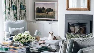 A country living room with blue sofas and a dog resting on a foot rest