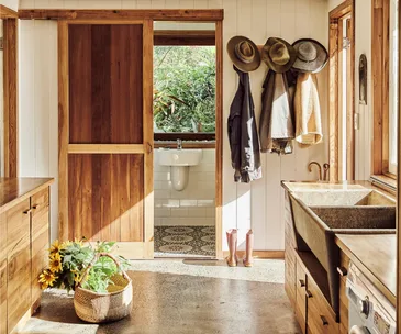 A country laundry room with concrete floors and timber cabinetry