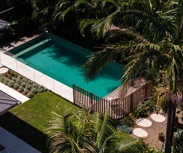 A tropical-style garden with a pool, palm trees and firepit area