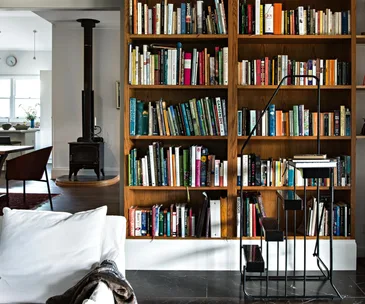 A cosy home library with timber shelves and a woodburning heater