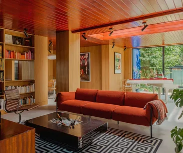 A mid-century lounge area with a geometric rug and built-in bookshelf