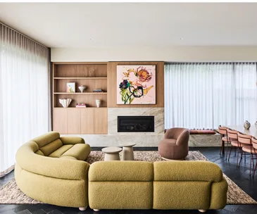 An open-plan living and dining area with a built-in fireplace and timber shelving