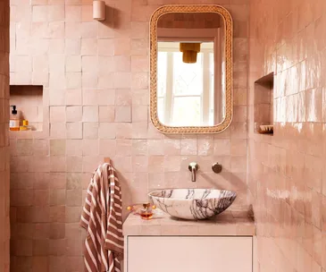 A pink tiled bathroom with a statement sink