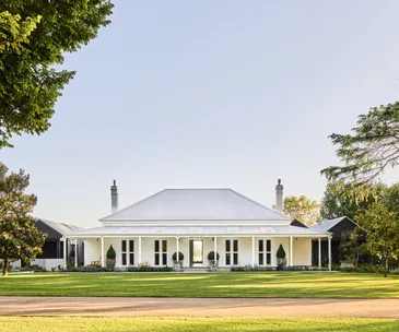 The exterior of a white Australian-style homestead with a verandah.