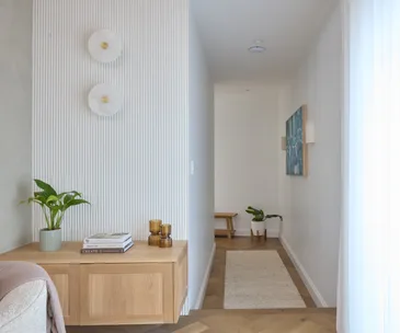 A hallway with a timber shelf and wall sconces