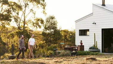 Homeowners Adam and Liam walking in their garden beside their modern white country house